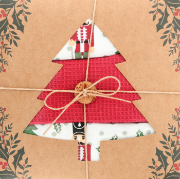 Zestaw świątecznych ścierek w brązowym opakowaniu z choinką z dziadka do orzechów, przewiązany sznurkiem.