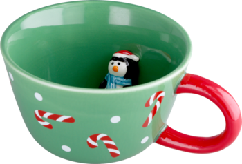 Zielony kubek świąteczny z czerwonym uchem, białymi kropkami i laskami cukrowymi. W środku figurka pingwina w czapce Mikołaja.