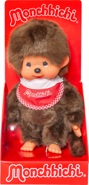 Monchhichi pluszowa lalka z brązowego futra, beżowa twarz, w czerwonym opakowaniu, z czerwono-białym śliniakiem.