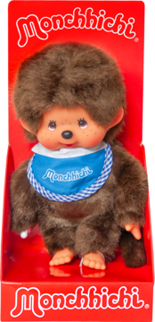 Pluszowa lalka Monchhichi w czerwonym pudełku, brązowa, z winylową twarzą i dłońmi, w niebieskim śliniaku.