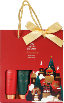 Czerwona torba prezentowa Tao Morri ze złotą kokardą, z dwoma tubkami kremów do rąk i świąteczną wycinanką.