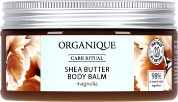 Organique Shea Butter Body Balm Magnolia, w szklanym słoiku ze srebrną pokrywką, brązowa etykieta z kwiatami magnolii.