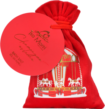 Czerwona welurowa saszetka z solą do kąpieli o zapachu Champagne, z okrągłą metką i złotą grafiką karuzeli.