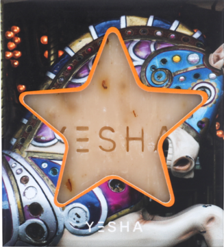 Świąteczne mydło YESHA gwiazdka z płatkami róży i masłem shea, beżowe z pomarańczową obwódką, na tle karuzeli.