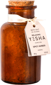 Sól do kąpieli Yesha Spicy Amber 350g, w brązowej szklanej butelce z korkiem i białą zawieszką, widok z przodu.