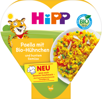 HiPP BIO Paella z kurczakiem i warzywami na białym talerzu, na żółto-zielonym tle w kształcie serca z tygrysem.