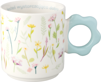 Biały ceramiczny kubek z kwiatowym wzorem i napisem, błękitny uchwyt w kształcie kwiatka, ujęcie z boku.