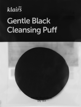 Czarny, okrągły Klairs Gentle Black Cleansing Puff, widok z przodu na tle opakowania z białym napisem.