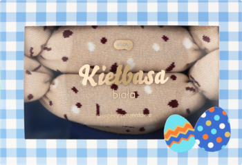 Widok z przodu skarpetek 'Kielbasa' w pudełku, imitujących kiełbaski, na tle niebieskiej kratki i pisanek.