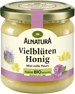 Alnatura Miód wielokwiatowy bio, złocistożółty i kremowy, w szklanym słoiku z fioletową etykietą i kwiatami, widok z przodu.