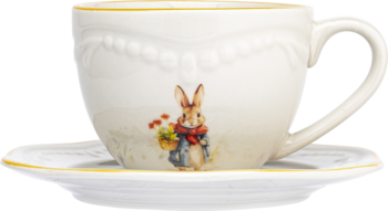 Biała filiżanka ze spodkiem ceramiczna, z żółtym brzegiem, wizerunkiem Królika Piotrusia i wypukłym wzorem. Ujęcie z przodu.