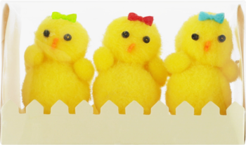 Trzy żółte pisklęta deserowe z kolorowymi kokardkami, stojące w białej, ząbkowanej tacce, widok z przodu.