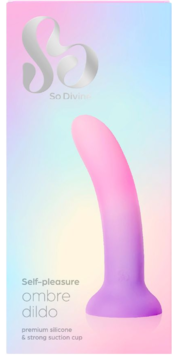 Opakowanie silikonowego dilda ombre So Divine. Ma różowo-fioletowy gradient, zakrzywiony kształt i przyssawkę. Widok z przodu na pastelowym tle.