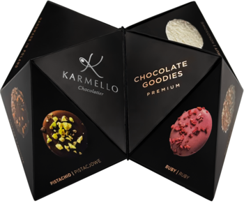 Czarna, geometryczna bombonierka Karmello, otwarta, z czekoladkami: pistacjowymi, rubinowymi, białymi. Widok z góry.