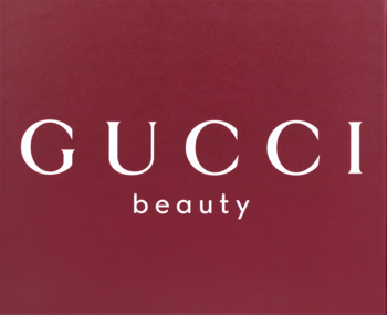 Logo Gucci Beauty, białe litery na bordowym tle, promujące męski zestaw Gucci Guilty o drzewno-przyprawowym zapachu.