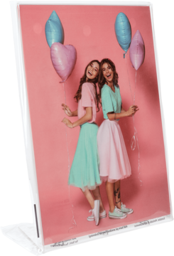 Fotoprint: dwie uśmiechnięte kobiety w pastelowych strojach i z balonami, na różowym tle, widok pod kątem.