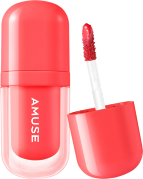 Koralowy błyszczyk Amuse w podłużnej butelce, obok aplikator z błyszczykiem, widok z przodu.