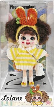 Lalka Lolane, zawieszka na telefon, w przezroczystym pudełku. Ma kręcone włosy, żółty sweter i czapkę z marchewką.