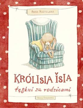 Okładka książki 'Królisia Isia tęskni za rodzicami' z królikiem na pasiastym fotelu. Ilustracja na tle w czerwone kropki.