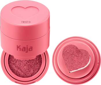 Kaja Cheeky Stamp róż w odcieniu Saucy. Otwarty różowy kompakt i osobno ukazany aplikator-serce z różem.