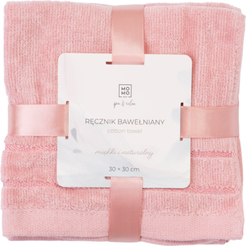 Różowy, puszysty ręcznik bawełniany 30x30 cm, złożony i przewiązany różową wstążką z białą etykietą.