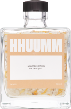 Sól do kąpieli Hhuumm Nagietek i Jaśmin w kwadratowej, szklanej butelce z pomarańczową etykietą i płatkami kwiatów.