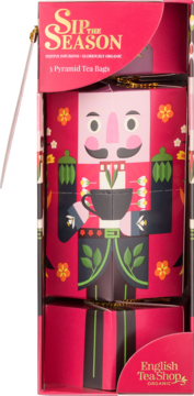 Czerwone opakowanie herbaty English Tea Shop w kształcie dziadka do orzechów, z 3 herbatkami piramidkami, trzymające filiżankę.