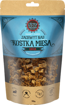 Pionowe ujęcie TRZYPSY DELUXE Kostka Mięsa Królik, 70g. Beżowa torebka z niebieską etykietą, widoczne brązowe kostki.
