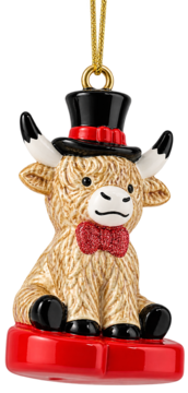 Urocza zawieszka: figurka krowy Highland w czarnym cylindrze, czerwonej muszce, siedząca na czerwonej podstawce.