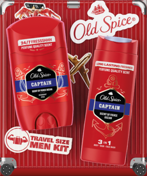 Old Spice Captain Travel Kit: czerwony dezodorant w sztyfcie i żel 3w1, na tle podróżnej walizki. Widok z góry.