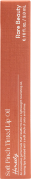 Rare Beauty Soft Pinch Tinted Lip Oil, odcień Honesty, na pionowym, brzoskwiniowym opakowaniu produktu.