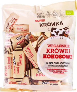 Biała torebka wegańskich krówek kokosowych BIO, z luźnymi cukierkami w papierkach z napisem 'Wiem co jem!'.