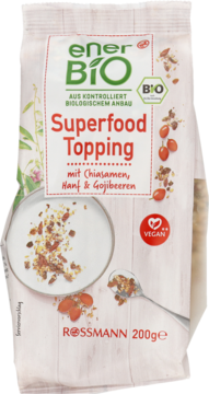 Biała torebka Enerbio Superfood Topping z chia, konopią i goji, widok z przodu, zielone logo i miseczka z dodatkiem.