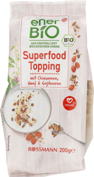 Biała torebka Enerbio Superfood Topping z chia, konopią i goji, widok z przodu, zielone logo i miseczka z dodatkiem.