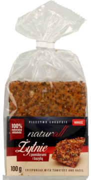 Frontowe ujęcie paczki pieczywa chrupkiego Naturall Żytnie z pomidorami i bazylią, widoczne zioła.