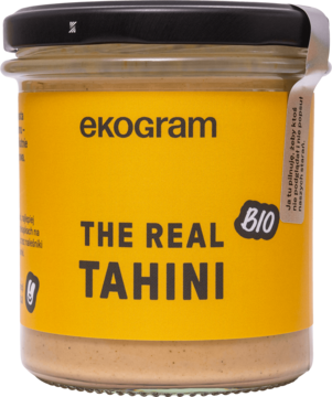 Słoik ekogram The Real Tahini BIO z czarną zakrętką i żółtą etykietą, widok z przodu, delikatna pasta sezamowa.