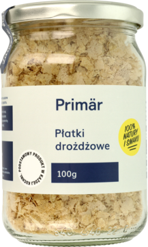 Szklany słoik płatków drożdżowych Primär 100g, widok z przodu. W środku jasnobeżowe płatki, biała etykieta z logo.