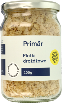 Szklany słoik płatków drożdżowych Primär 100g, widok z przodu. W środku jasnobeżowe płatki, biała etykieta z logo.