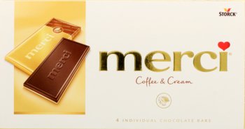 Białe pudełko czekoladek Merci Coffee & Cream, obok dwa batony: kawowy i biała czekolada. Widok z przodu.