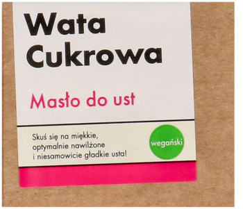 Wegańskie masło do ust Wata Cukrowa, zbliżenie na białą etykietę produktu z czarnym napisem i różowym paskiem.