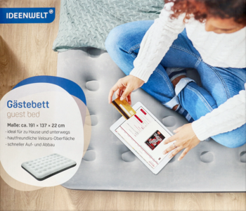 Ideenwelt dmuchany materac, szary, z welurową powierzchnią. Osoba siedzi na nim, trzymając tablet. Widok z góry.