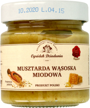 Szklany słoik Musztardy Wąsoskiej Miodowej, o żółto-brązowym kolorze z widocznymi nasionami gorczycy, widok z przodu.