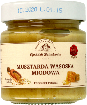 Szklany słoik Musztardy Wąsoskiej Miodowej, o żółto-brązowym kolorze z widocznymi nasionami gorczycy, widok z przodu.