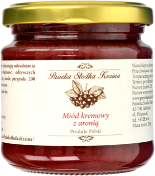 Słoik miodu kremowego z aronią, zlotą nakrętka, widok z przodu. Ciemnoczerwony miód, biała etykieta z rysunkiem aronii.