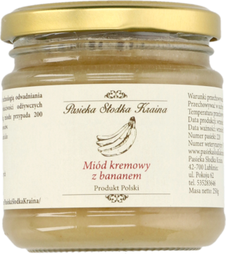 Kremowy miód z bananem Pasieka Słodka Kraina, słoik 250g, jasny kolor, złota zakrętka, z przodu etykieta z bananami.