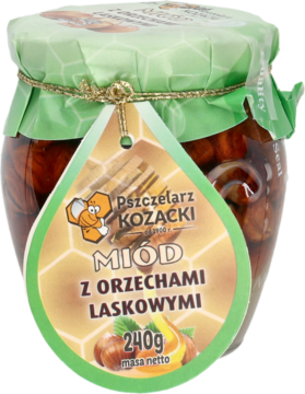 Miód Pszczelarz Kozacki z orzechami laskowymi w szklanym słoiku, z zieloną etykietą, widok z przodu.