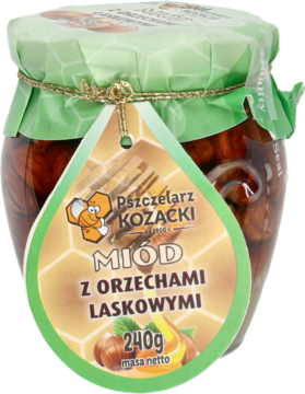 Miód Pszczelarz Kozacki z orzechami laskowymi w szklanym słoiku, z zieloną etykietą, widok z przodu.