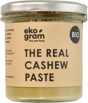Ekologiczna pasta nerkowcowa The Real Cashew Paste BIO w szklanym słoiku, beżowa etykieta, widok z przodu.