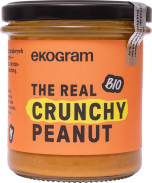 Ekogram BIO The Real Crunchy Peanut, ekologiczne masło orzechowe w słoiku z pomarańczową etykietą, widok z przodu.