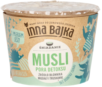 Inna Bajka Musli Pora Detoksu w brązowym kubku z zielonymi napisami, z migdałami i truskawkami, widok z przodu.